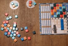 Top view of a strategy board game with colorful tiles and game board on a wooden table.