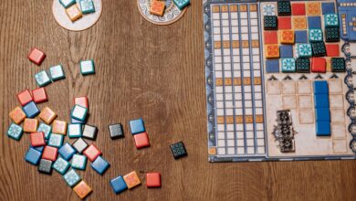 Top view of a strategy board game with colorful tiles and game board on a wooden table.