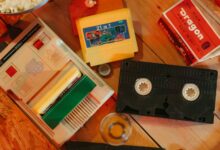 Vintage gaming console with cartridges and VHS tape on wooden surface, nostalgic theme.