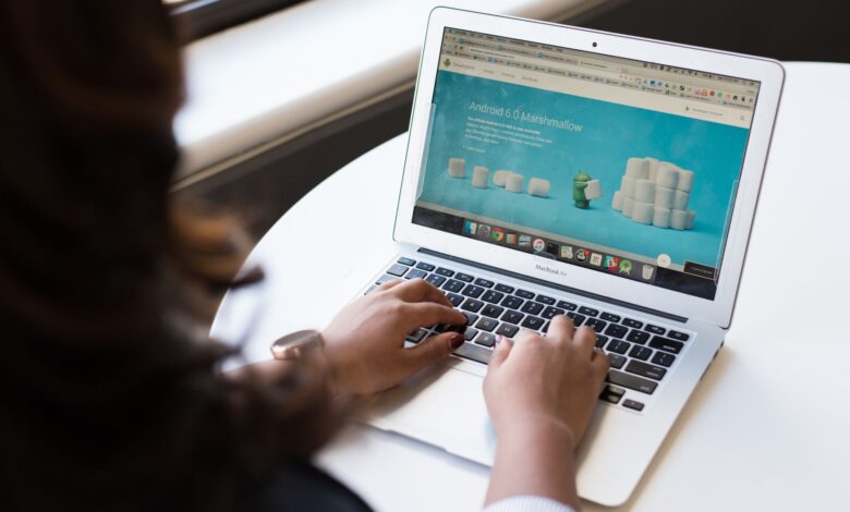 Businesswoman working on laptop with Android 6.0 Marshmallow webpage open.