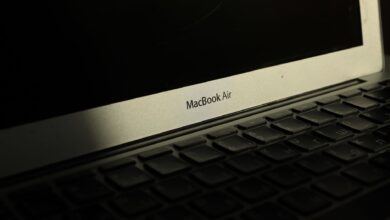 Close-up of a sunlit MacBook Air laptop showcasing its keyboard and screen with shadow effects.