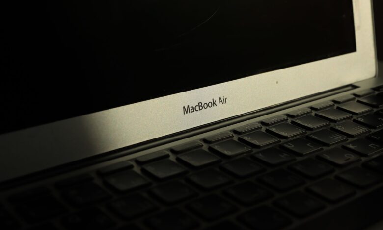 Close-up of a sunlit MacBook Air laptop showcasing its keyboard and screen with shadow effects.