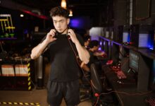 A serious young man in a gaming lounge with headphones, embodying the modern e-sports culture.