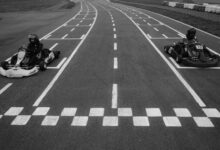 Two go-karts at the starting line on a racetrack, ready for a competitive race.