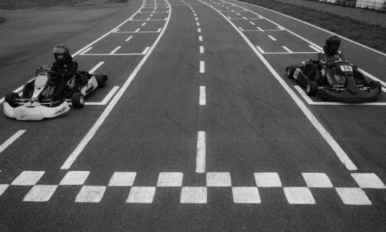 Two go-karts at the starting line on a racetrack, ready for a competitive race.