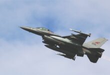 A dynamic shot of an F-16 military jet soaring through a clear sky, showcasing advanced aviation technology.