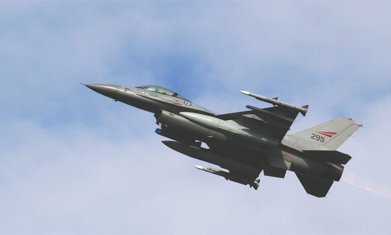 A dynamic shot of an F-16 military jet soaring through a clear sky, showcasing advanced aviation technology.