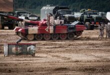 A military training exercise featuring tanks and soldiers on a field, showcasing armored vehicle operations.