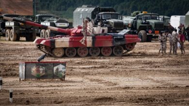 A military training exercise featuring tanks and soldiers on a field, showcasing armored vehicle operations.