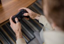 Detailed view of a person holding a gaming controller indoors, emphasizing the gameplay action.