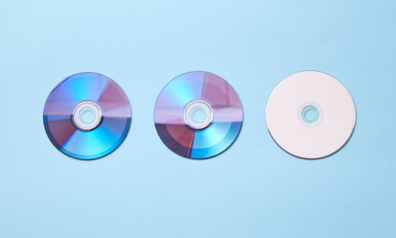 Three classic compact discs with a nostalgic tone on a pastel blue background.