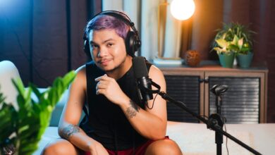 Musician sitting indoors with headphones and microphone, ready to record a podcast.