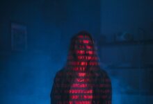 A mysterious silhouette with red binary code projected over the face, set against a dark, moody background.