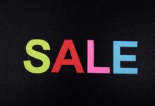 Multicolor letters spelling SALE on a textured black surface, perfect for promotional use.