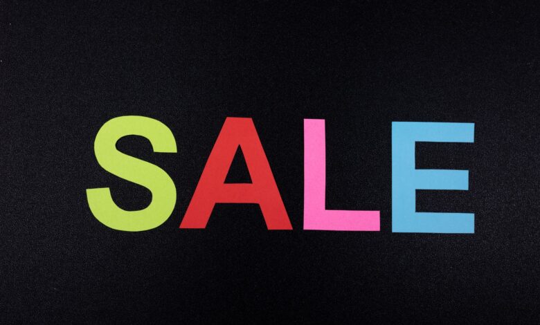 Multicolor letters spelling SALE on a textured black surface, perfect for promotional use.