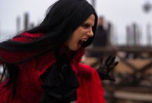 Woman in a vampire costume with black hair and red dress in Venice, Italy.