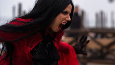 Woman in a vampire costume with black hair and red dress in Venice, Italy.