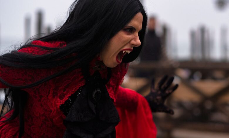 Woman in a vampire costume with black hair and red dress in Venice, Italy.