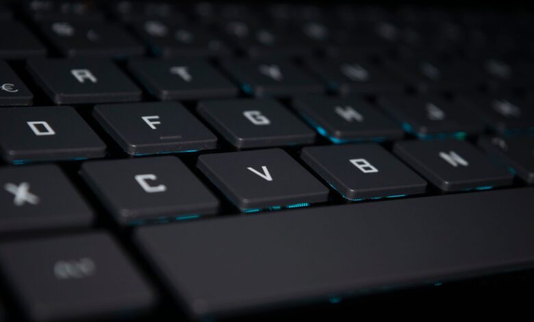 A close-up shot of a backlit keyboard in a dark setting, highlighting the keys.