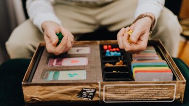 Person playing a board game with colorful pieces and cards indoors, focused and engaging.