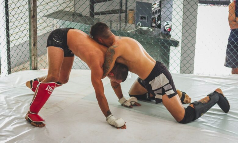 Two men engaged in a Brazilian Jiu-Jitsu grappling match in an indoor gym.