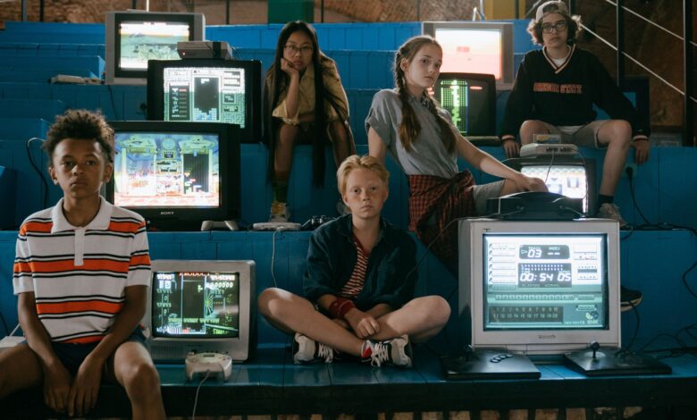 Group of teenagers interacting with old school video game consoles, evoking 80s nostalgia.