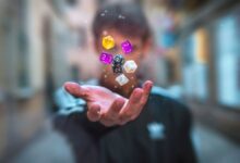 Colorful dice float above a hand with a blurred background, creating a dynamic and abstract visual.