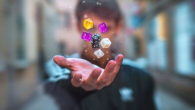 Colorful dice float above a hand with a blurred background, creating a dynamic and abstract visual.
