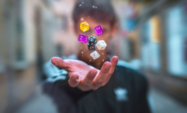 Colorful dice float above a hand with a blurred background, creating a dynamic and abstract visual.