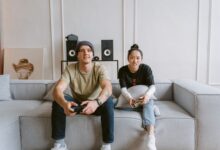 Man and woman playing video games on a couch, conveying a relaxed and fun atmosphere.