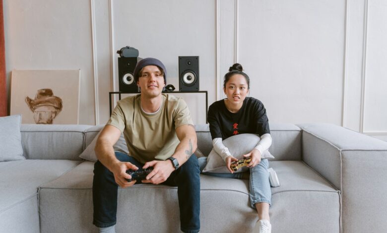 Man and woman playing video games on a couch, conveying a relaxed and fun atmosphere.