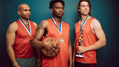 Three basketball players celebrating with medals and a trophy in victory pose.
