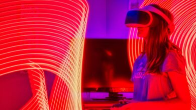 Woman immersed in virtual reality while surrounded by dynamic neon lights indoors.