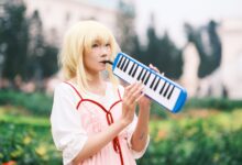 Anime cosplayer plays melodica in a vibrant park setting in Vietnam.