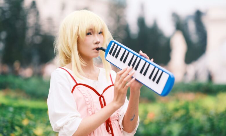 Anime cosplayer plays melodica in a vibrant park setting in Vietnam.