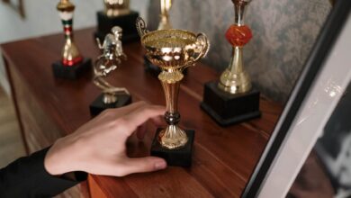 A close-up of a hand reaching for a shiny trophy on a wooden shelf, symbolizing success.