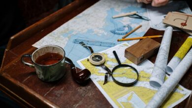 Overhead view of navigation tools with maps, compass, and coffee cup.