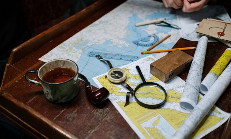 Overhead view of navigation tools with maps, compass, and coffee cup.