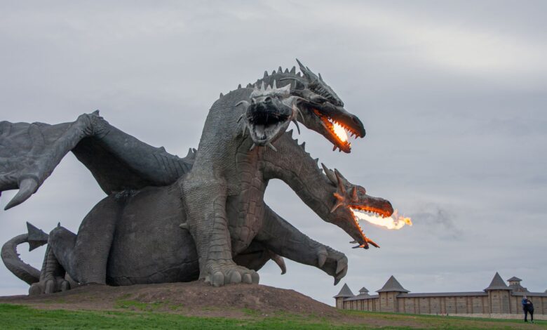 Majestic dragon sculpture breathing fire, set in an open park area, perfect attraction for fantasy lovers.