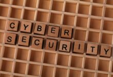 Wooden letter blocks spelling 'CYBER SECURITY' on a wooden grid background for data protection themes.