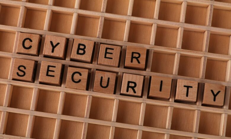 Wooden letter blocks spelling 'CYBER SECURITY' on a wooden grid background for data protection themes.