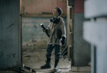 Young explorer in a gas mask investigates a ruined, desolate building with a flashlight.