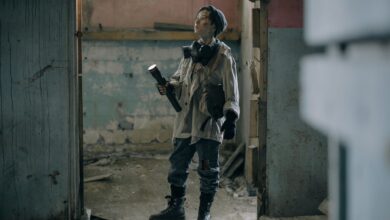 Young explorer in a gas mask investigates a ruined, desolate building with a flashlight.