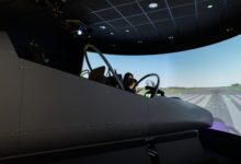 A female pilot operates a flight simulator in an advanced training facility.