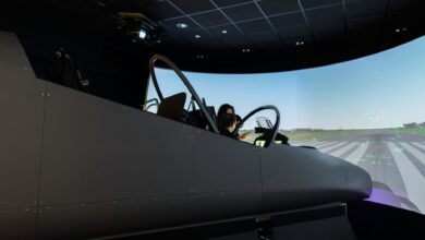 A female pilot operates a flight simulator in an advanced training facility.