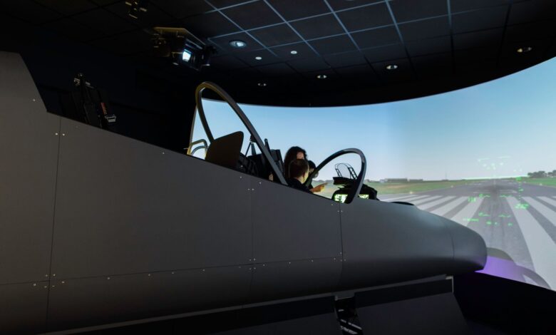 A female pilot operates a flight simulator in an advanced training facility.