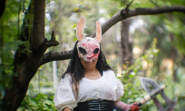Cosplayer in a forest wearing a distinctive mask, conveying a mysterious theme.