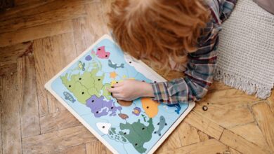 A child engaged with a colorful educational world map puzzle on a wooden floor, enhancing their problem-solving skills.