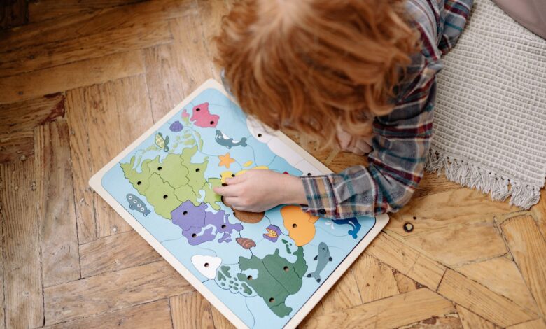 A child engaged with a colorful educational world map puzzle on a wooden floor, enhancing their problem-solving skills.