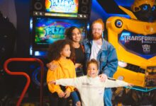 A cheerful family posing with arcade games and robots, capturing a vibrant amusement moment.